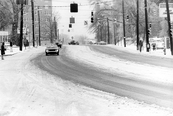 A few cars and pedestrians getting around slick streets in Snow Jam 82