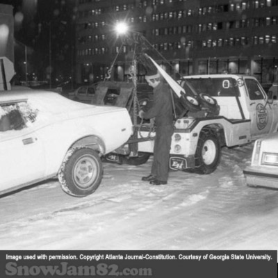 Tow truck driver tows away a vehicle during a snow storm in downtown Atlanta - January 13, 1982 – AJC File